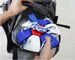 Person holding a colorful object with blue, red, and white elements against a backpack background.