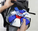 Person holding a colorful object with blue, red, and white elements against a backpack background.